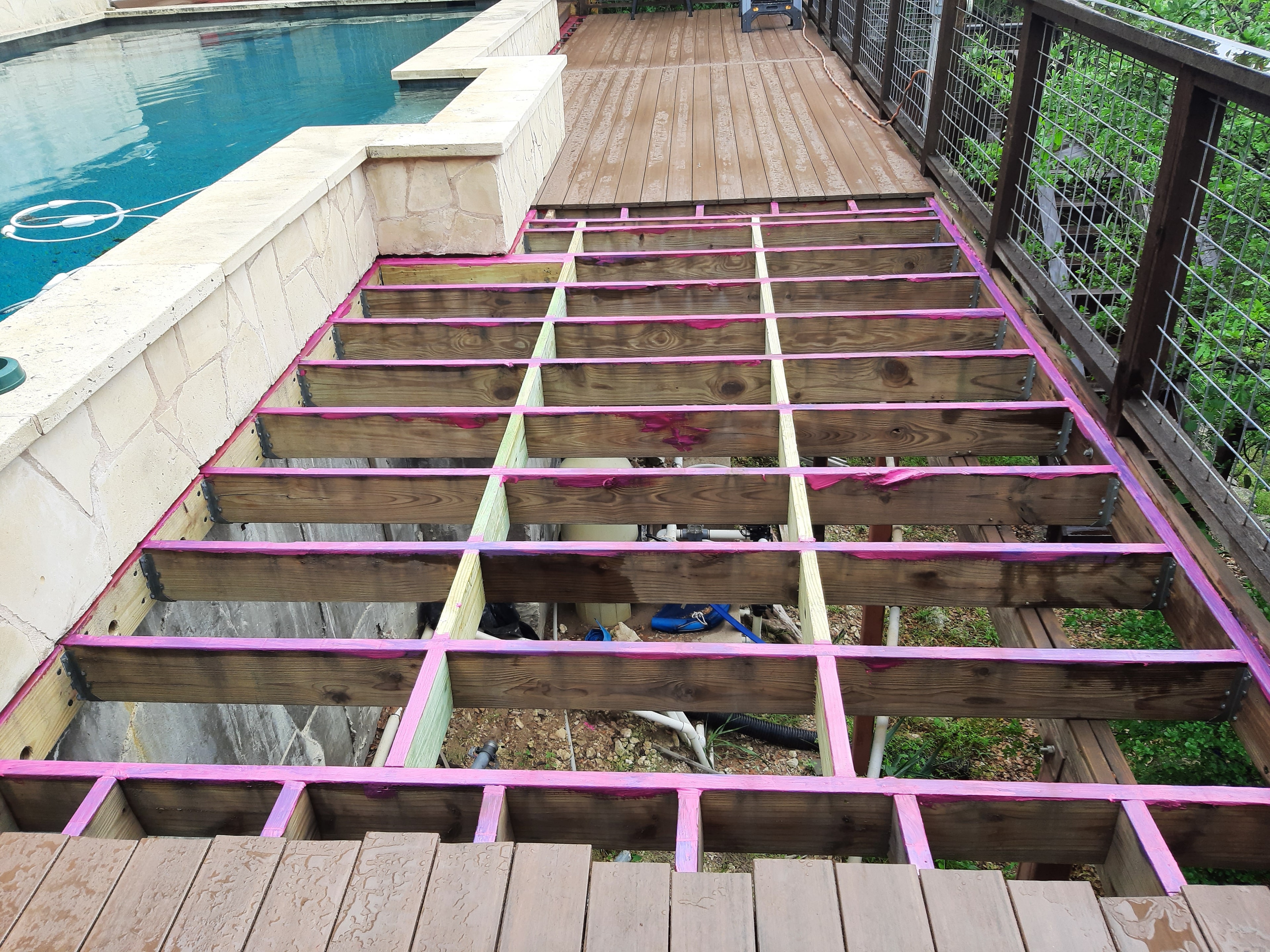 Deck ceiling framing with pink tape and wood joists viewed from below