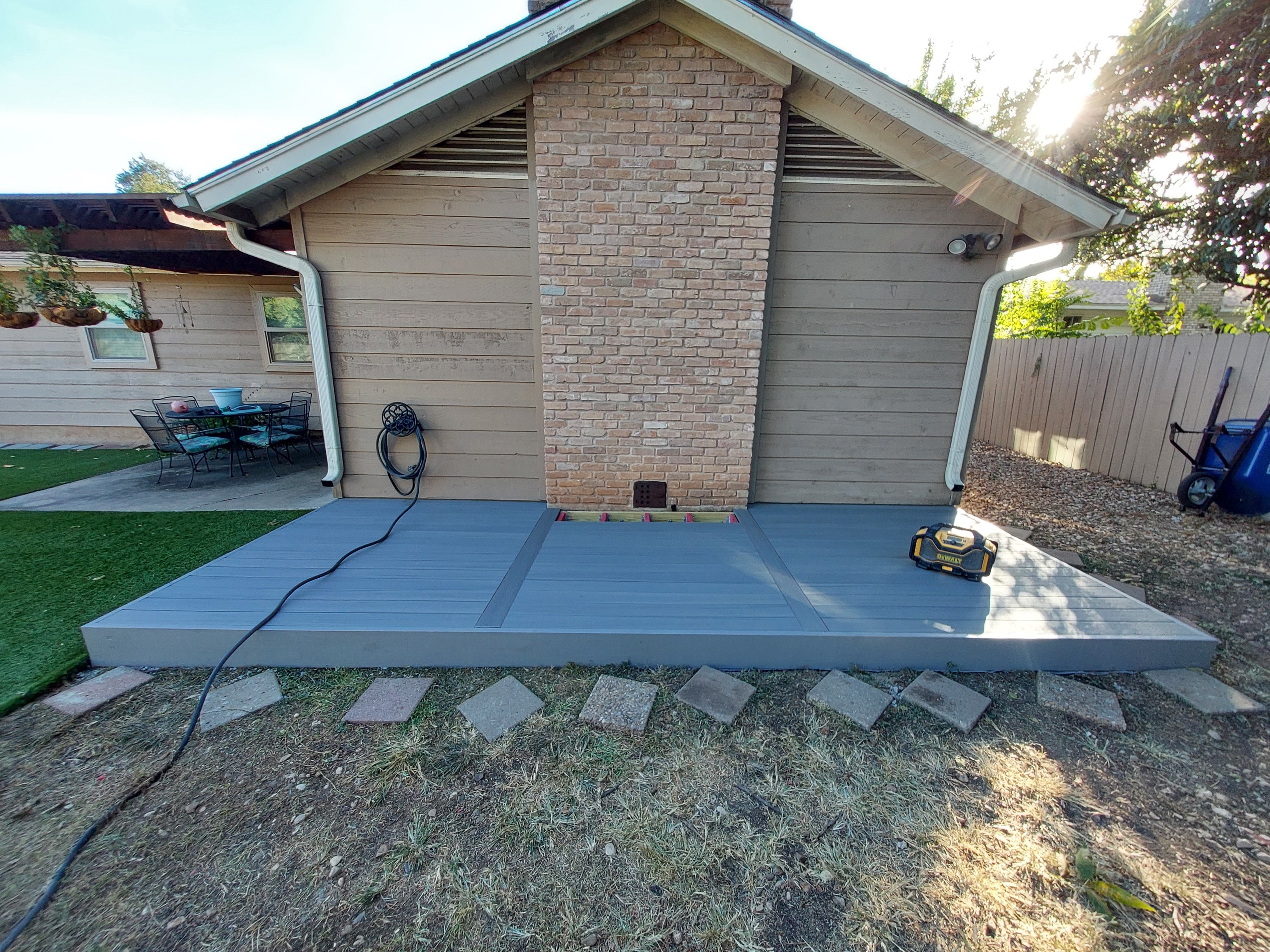 Finished gray composite deck spanning full width of brick home exterior
