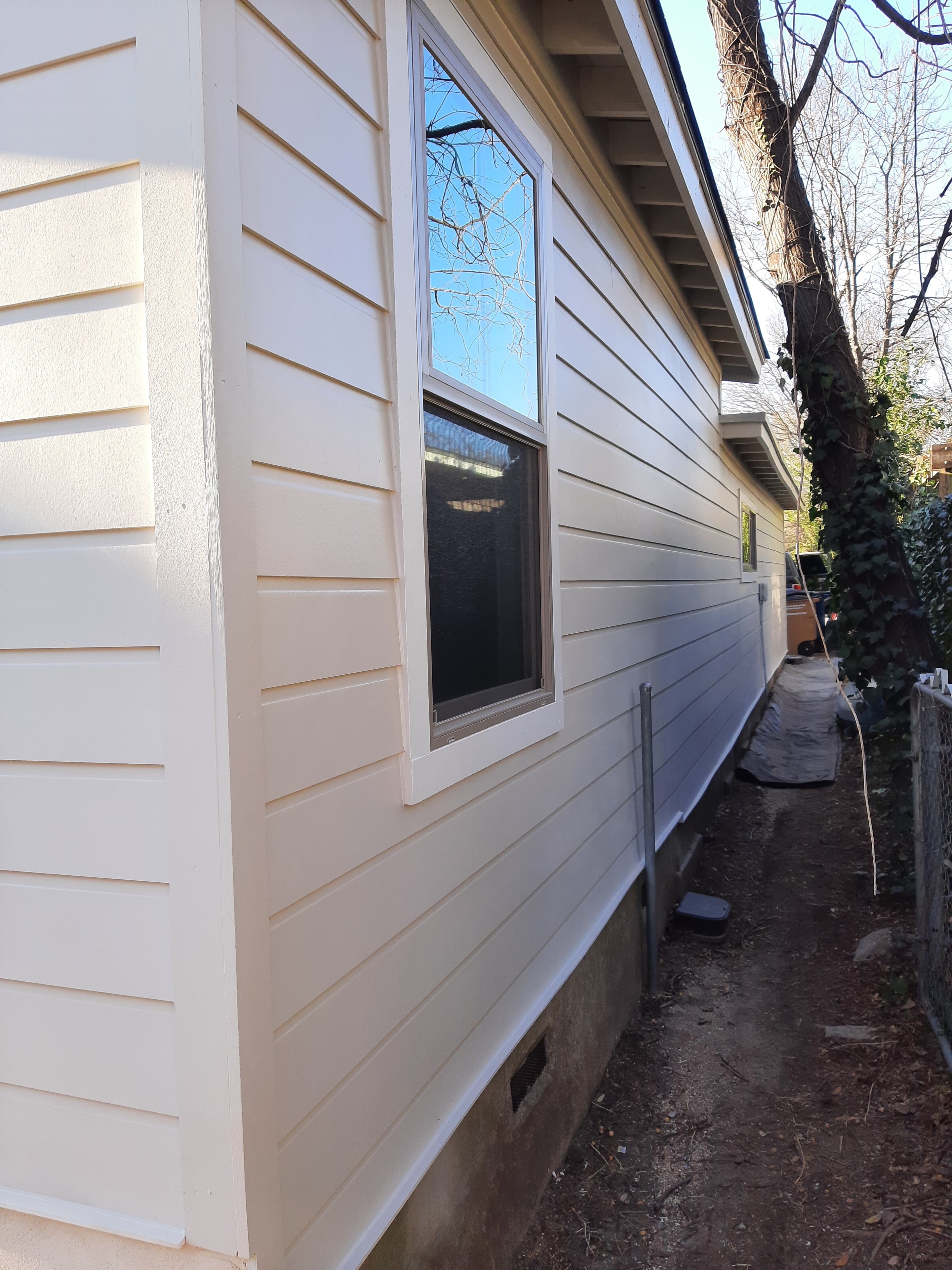 Freshly painted cream horizontal siding with new window trim on home exterior