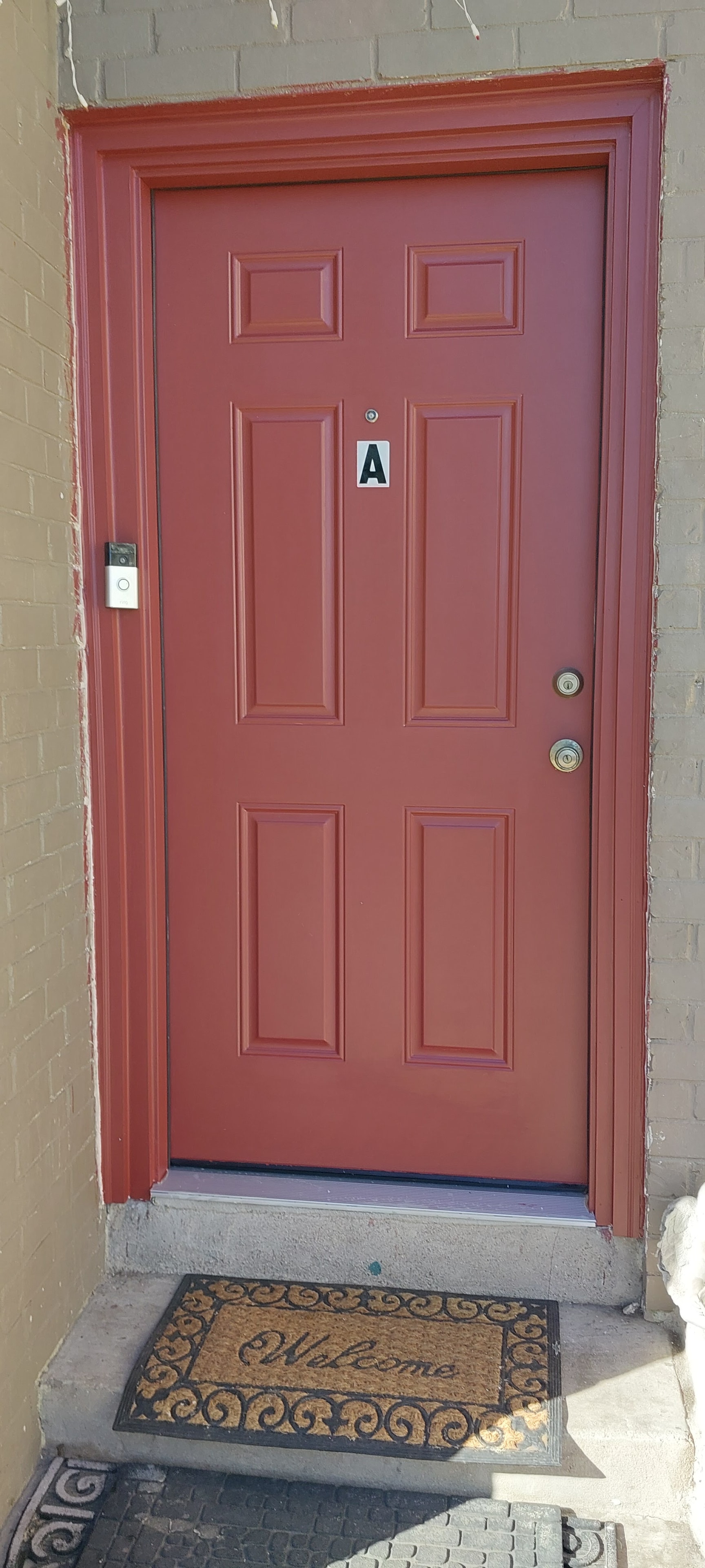 Freshly painted red entry door with white trim on brick building exterior