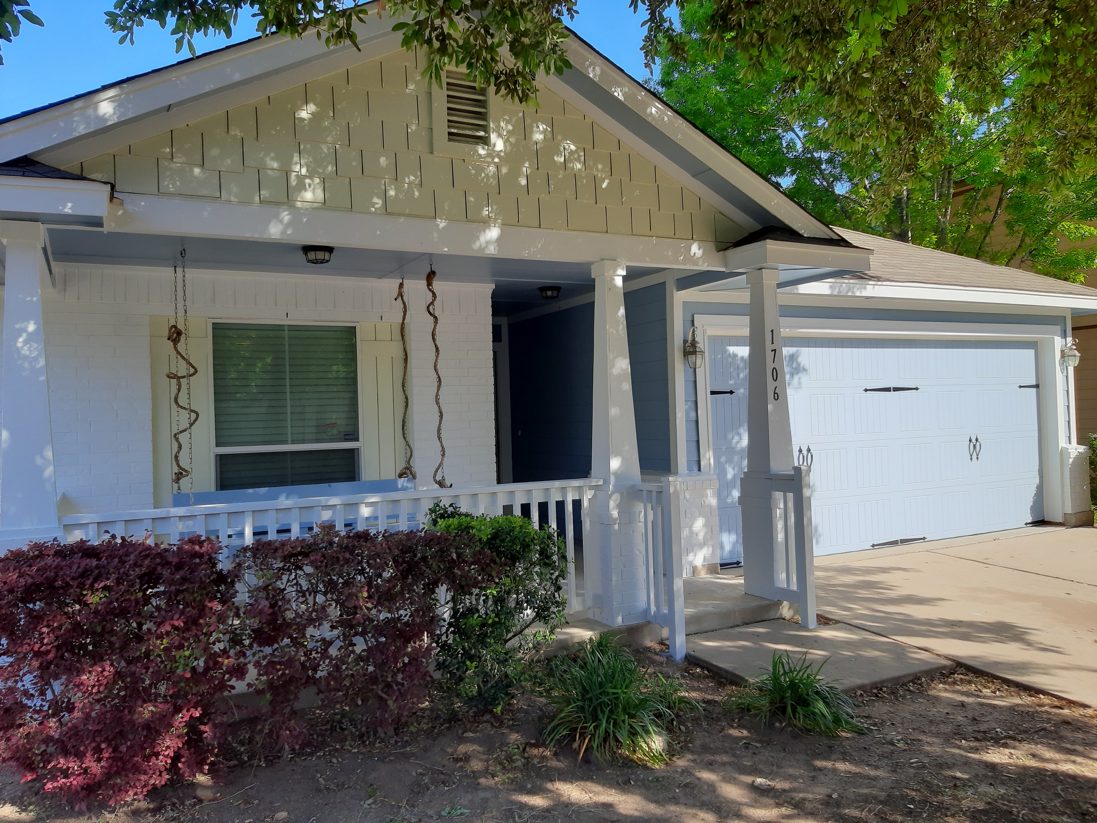 Freshly painted white house exterior with garage and porch landscaping