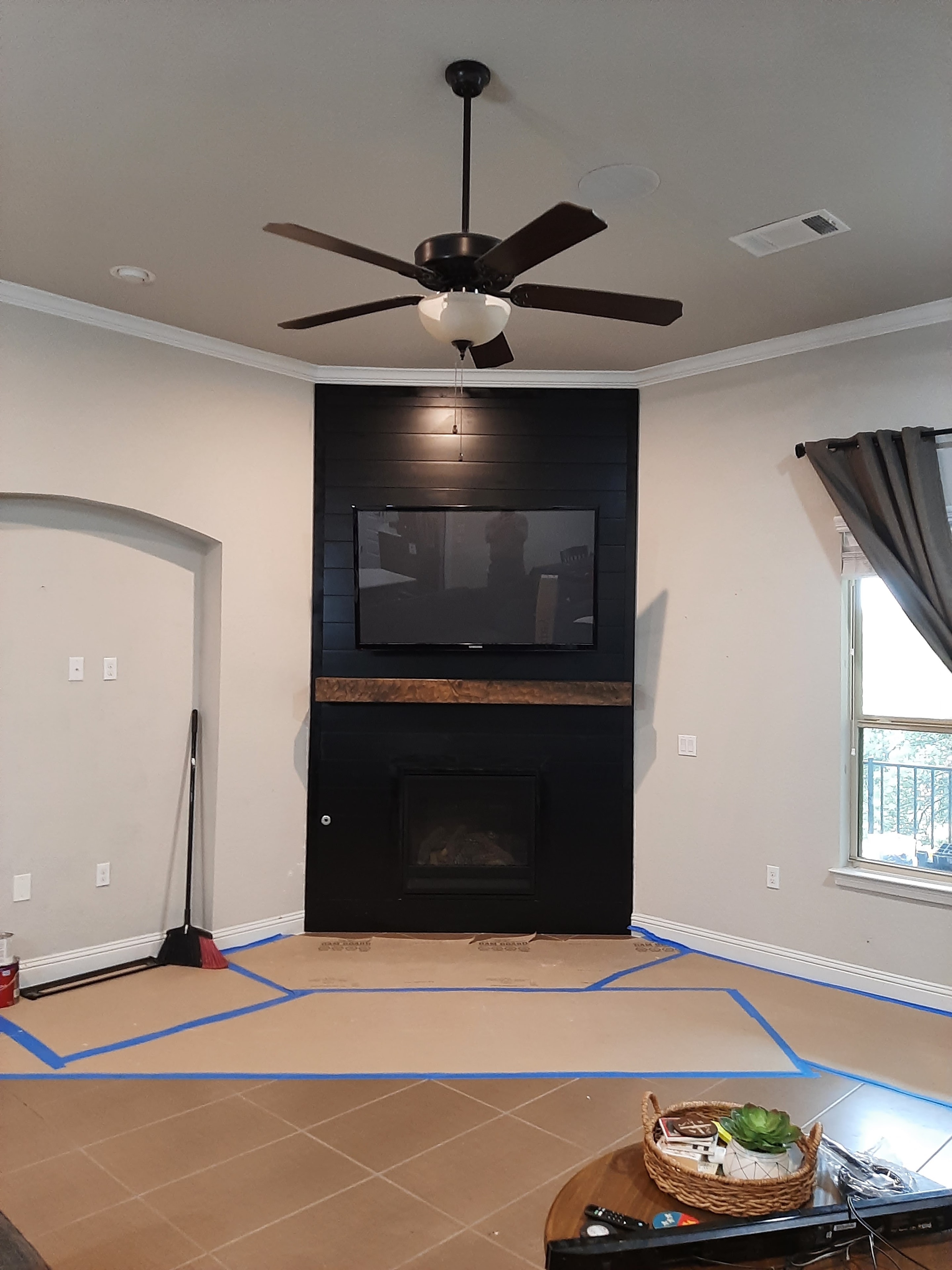 Finished living room with black shiplap fireplace feature wall and ceiling fan
