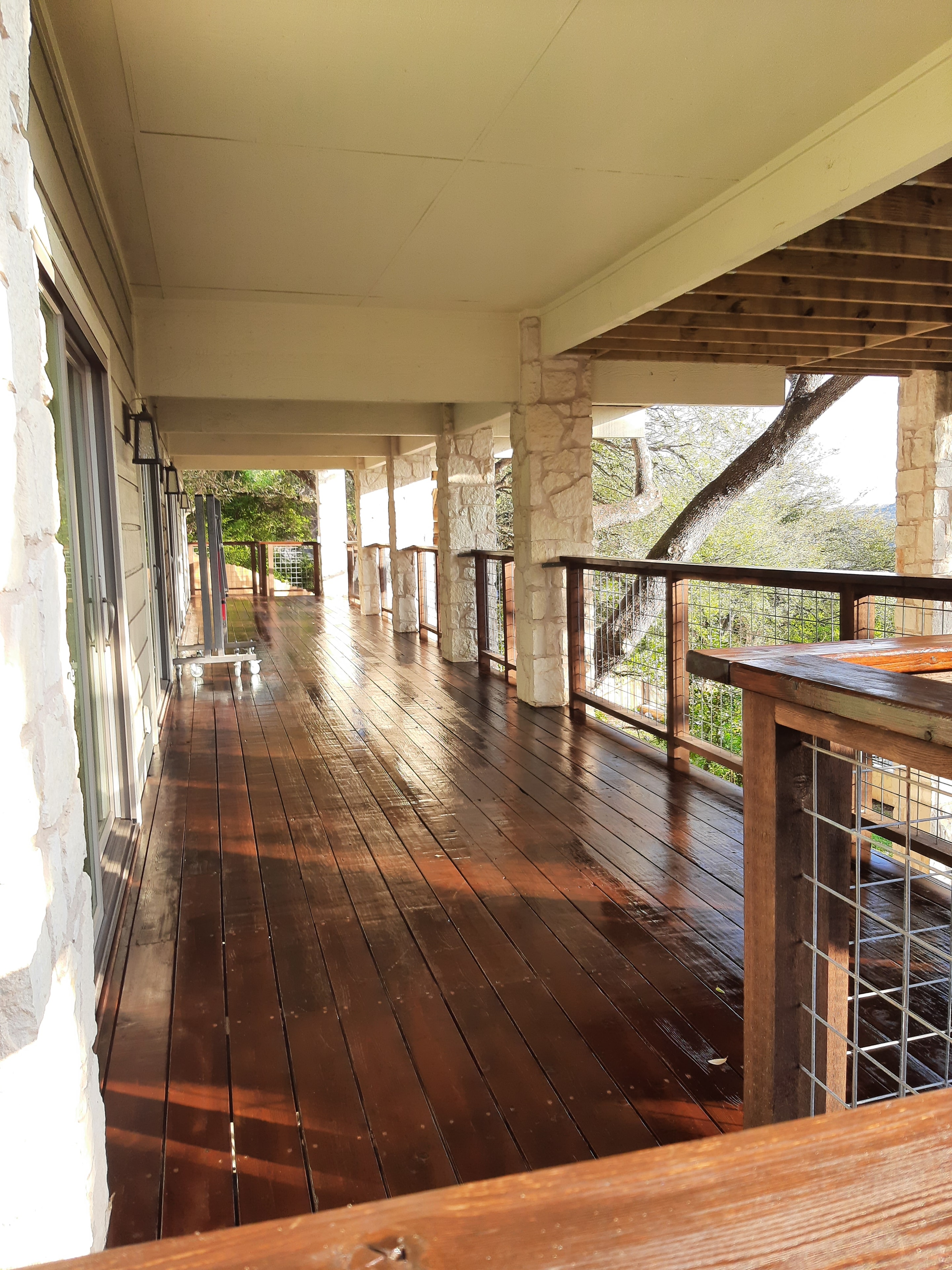 Freshly stained deck boards and pergola structure beside stone wall walkway