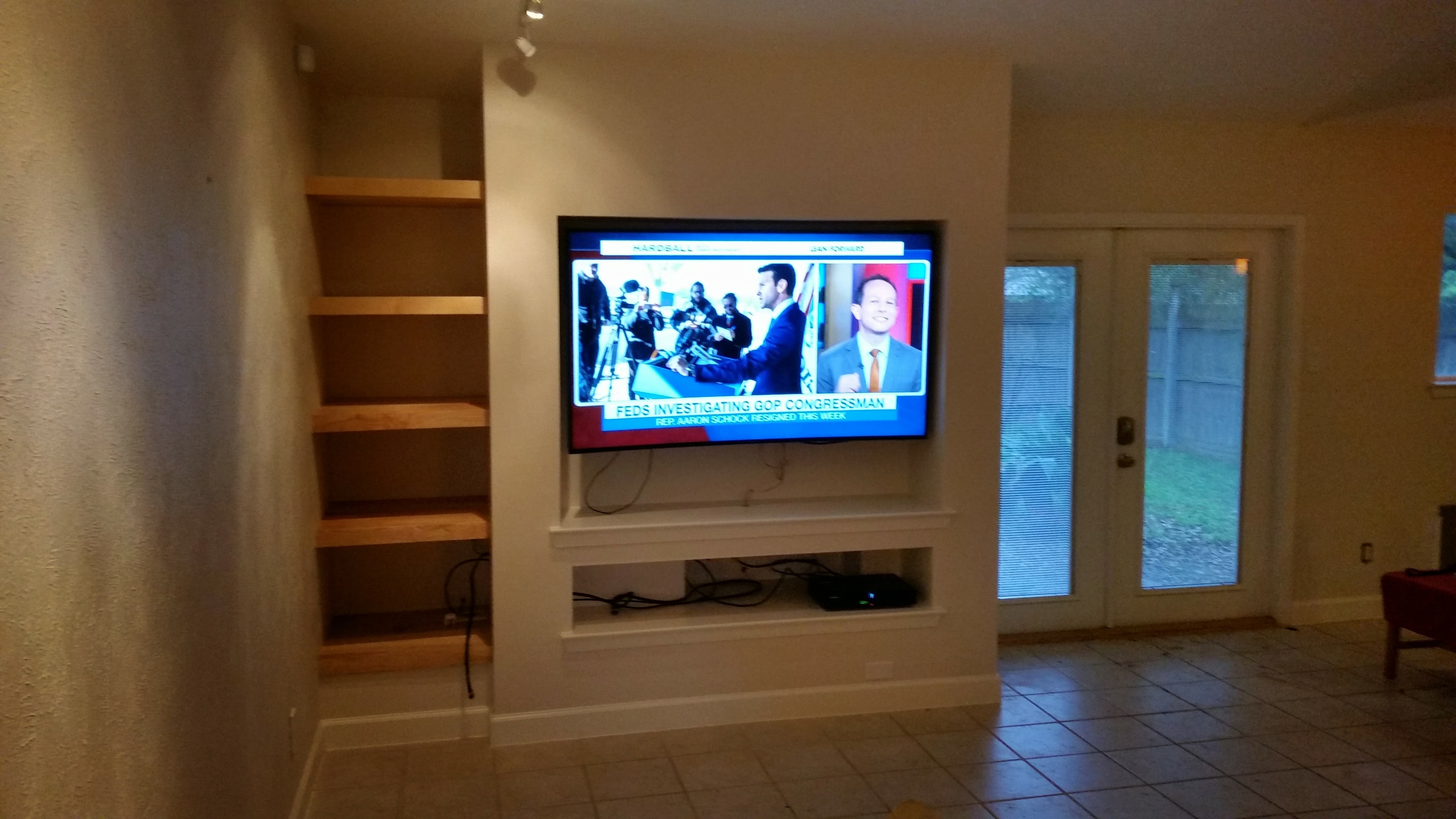 Finished TV entertainment center converted from old fireplace with built-in shelving and mounted flat-screen