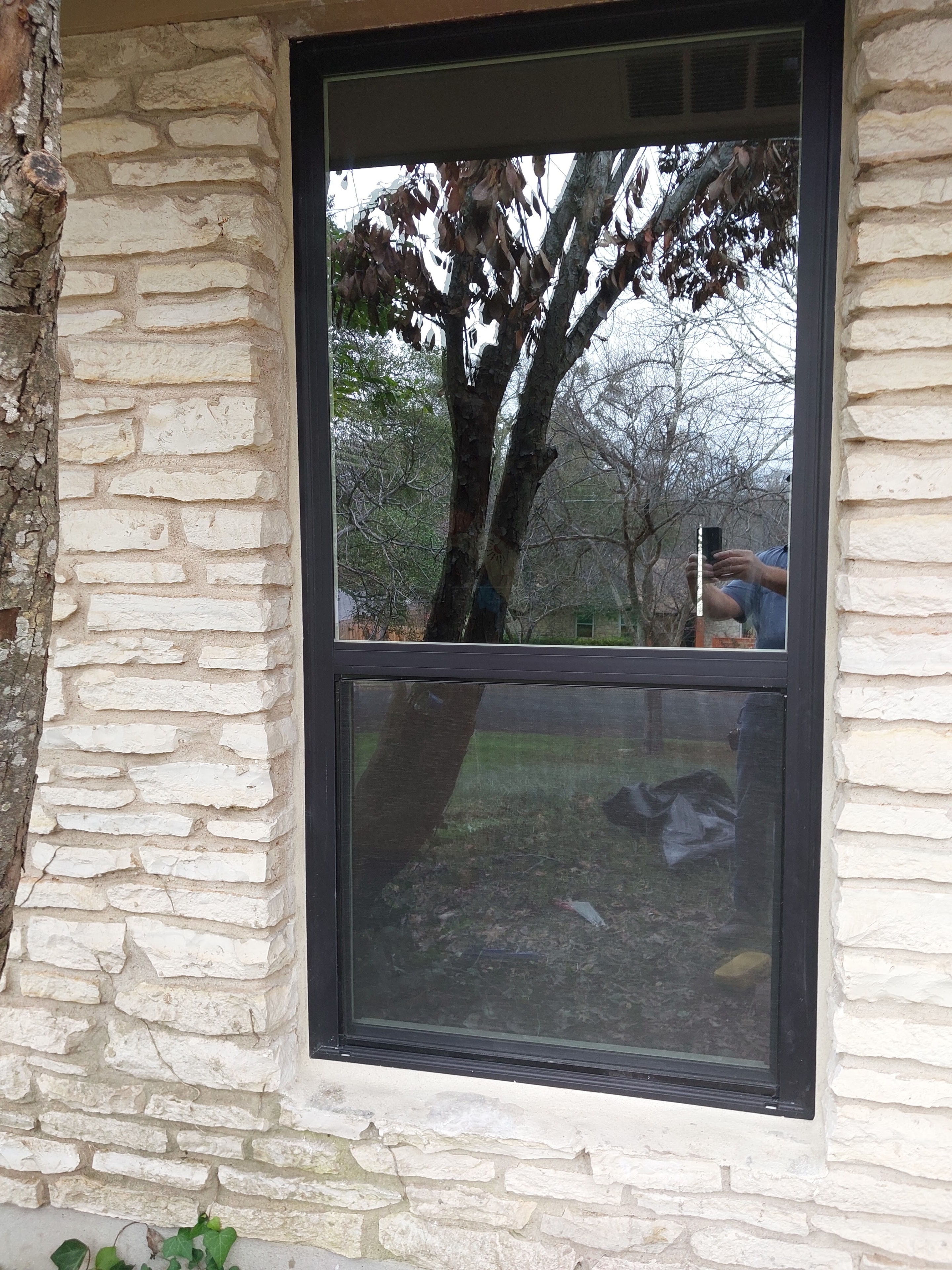 Black-framed window installed in stone wall exterior