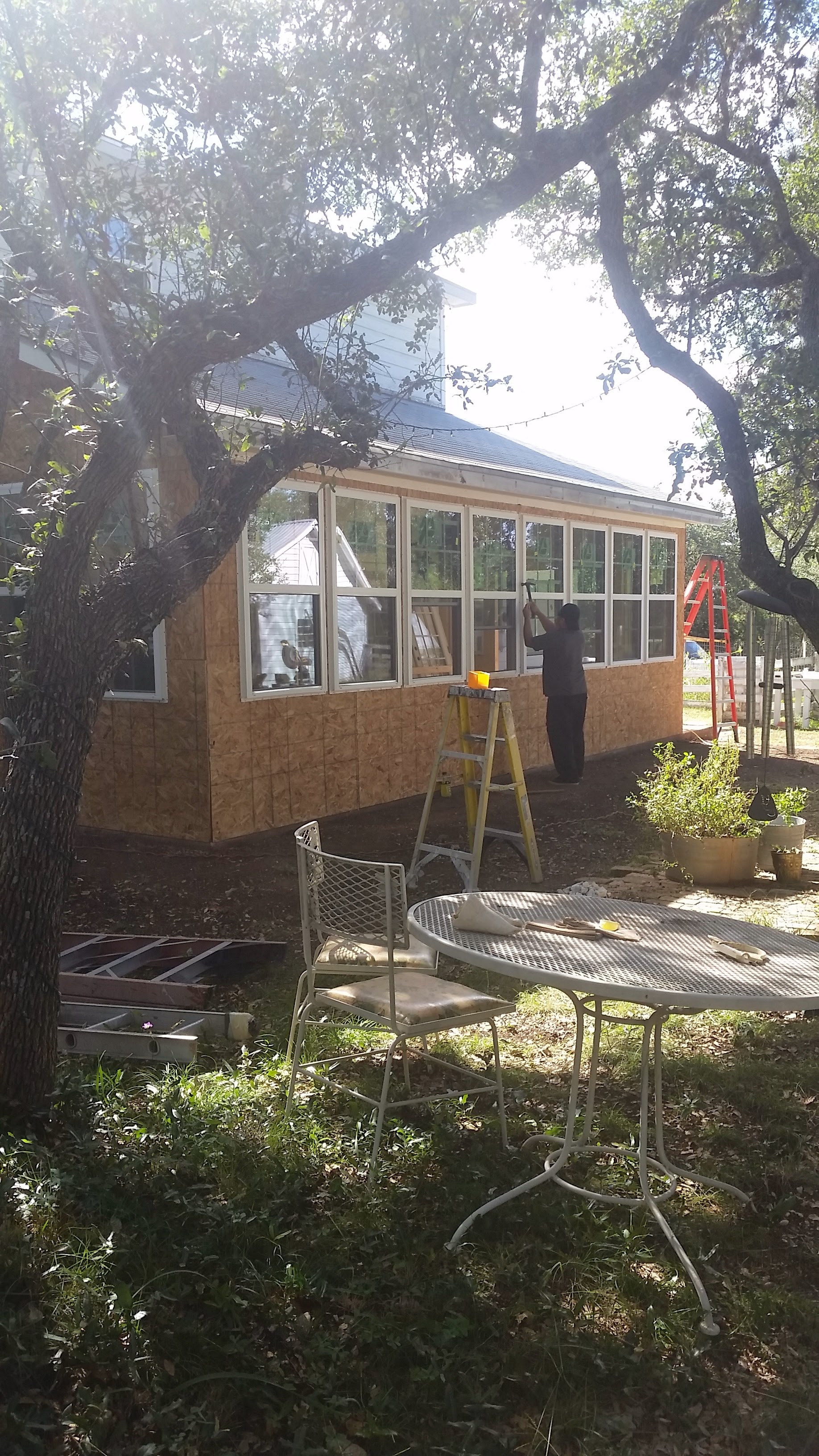 Worker installing multiple windows on sunroom addition with OSB sheathing